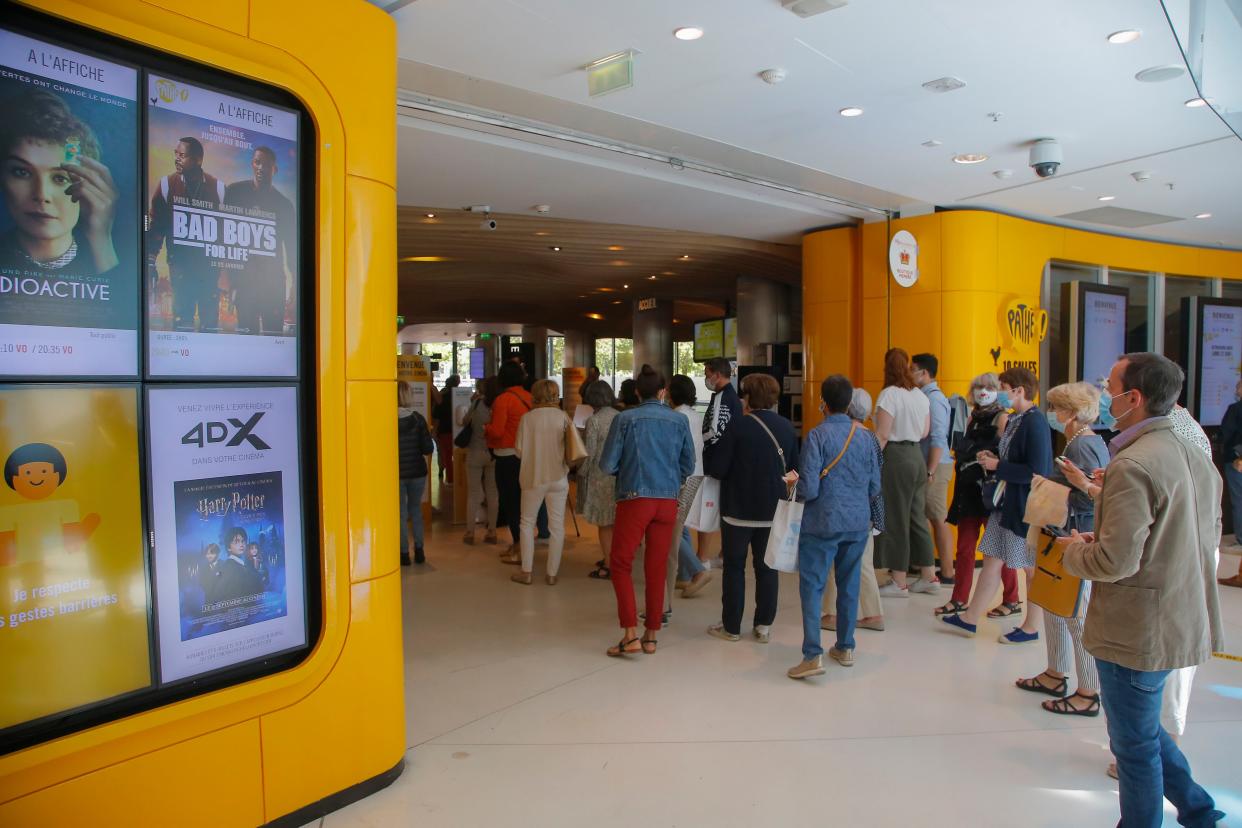 People wear protective masks as they get into a movie theater in Paris, France on Monday, June 22, 2020. Movie theaters are reopening across the country after three months of closure due to the COVID-19 lockdown measures.