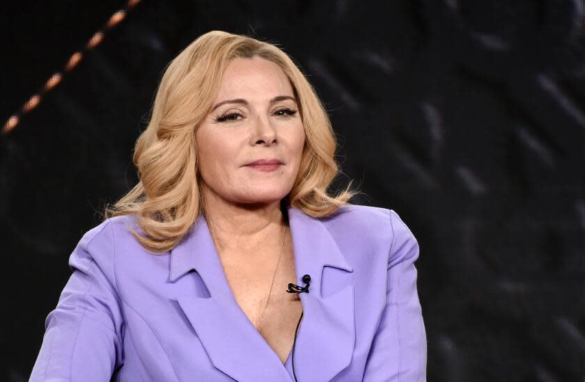 Kim Cattrall in a lavender suit sits for a panel discussion