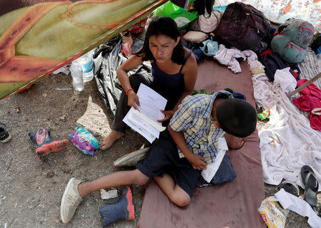 Honduran migrant Sofia Yamile Gomez, 37, and her son take a break from traveling in a caravan during their journey to the U.S., in Matias Romero, Mexico April 3, 2018. REUTERS/Henry Romero