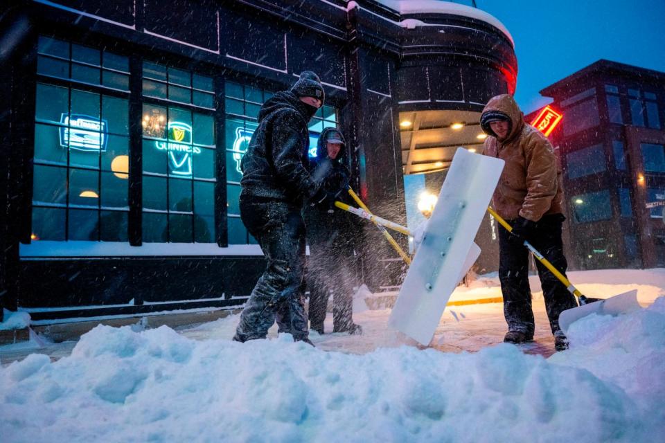 PHOTO: Men shovel snow off the sidewalk in Ankeny, Iowa, on Jan. 12, 2024. (Jim Watson/AFP via Getty Images)