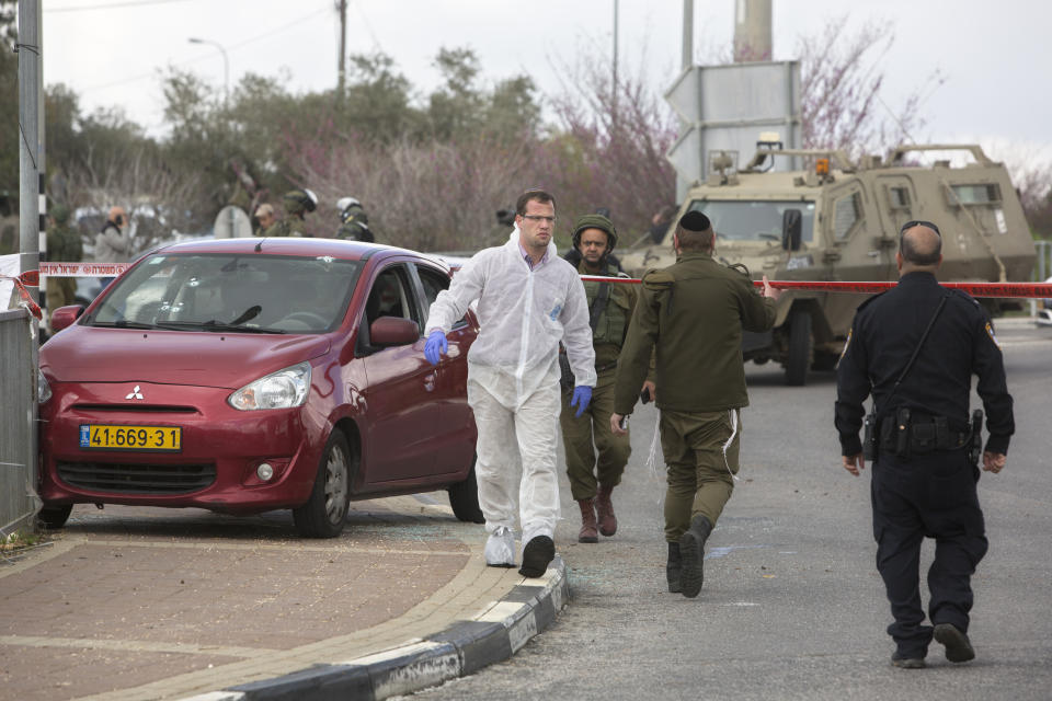 An Israeli forensic expert, right, inspects the scene of an attack near the West Bank Jewish settlement of Ariel, Sunday, March 17, 2019. The Israeli military says a Palestinian killed an Israeli and seriously wounded two others in a West Bank shooting and stabbing spree before fleeing and setting off a massive manhunt. (AP Photo/Sebastian Scheiner)