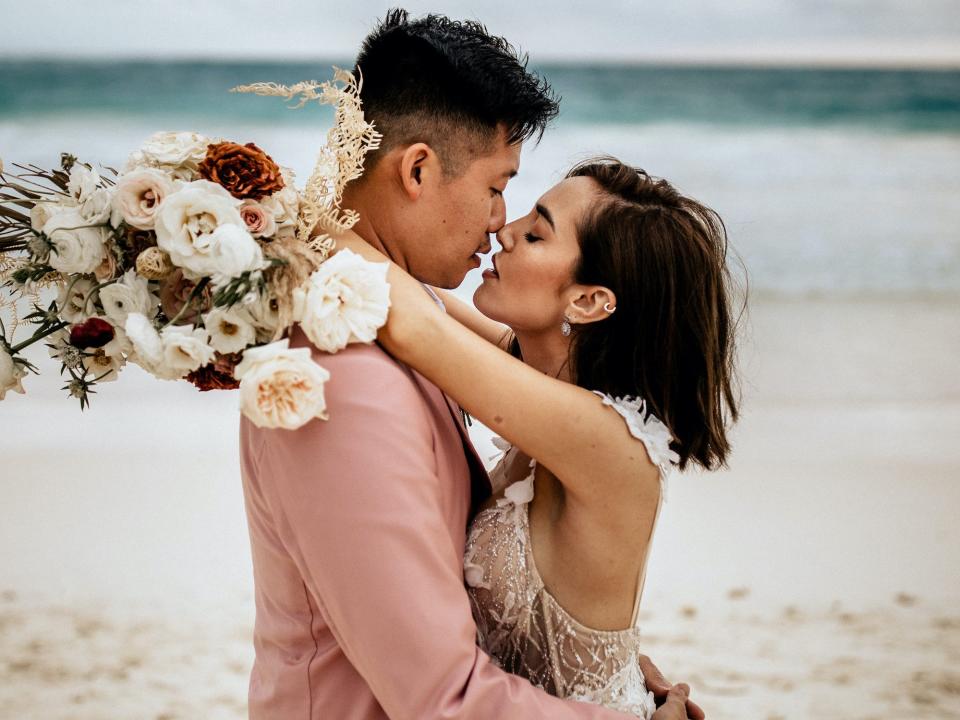 The Baks kissing on a beach on their wedding day