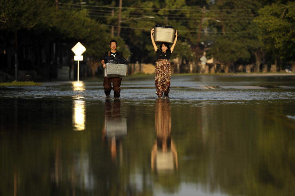 FILE - In this Monday, Sept. 4, 2017 file photo, Mariko Shimmi, right, helps carry items out of the home of Ken Tani in a neighborhood still flooded from Harvey in Houston. Some neighborhoods around Houston remain flooded and thousands of people have been displaced by torrential rains and catastrophic flooding since Harvey slammed into Southeast Texas last week. According to a scientific report from the United Nations released on Wednesday, March 13, 2019, climate change, a global major extinction of animals and plants, a human population soaring toward 10 billion, degraded land, polluted air, and plastics, pesticides and hormone-changing chemicals in the water are making the planet an increasing unhealthy place for people. (AP Photo/Gregory Bull)