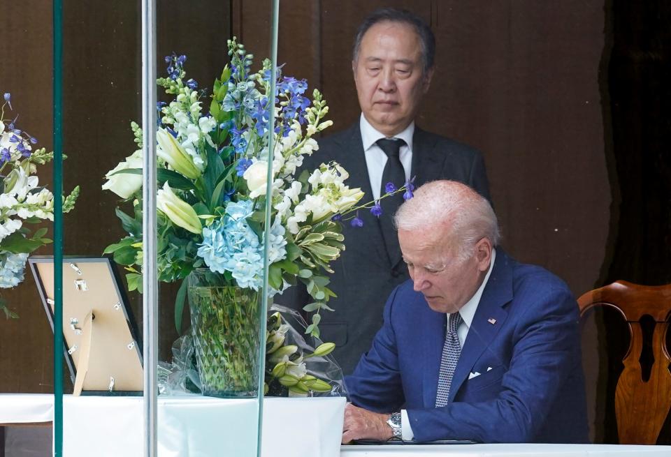 President Joe Biden signs a condolence book at the Japanese ambassador's residence in Washington, Friday, July 8, 2022, for former Japanese Prime Minister Shinzo Abe who was assassinated on Friday while campaigning. Japanese Ambassador to the United States Koji Tomita looks on. (AP Photo/Susan Walsh) ORG XMIT: DCSW412