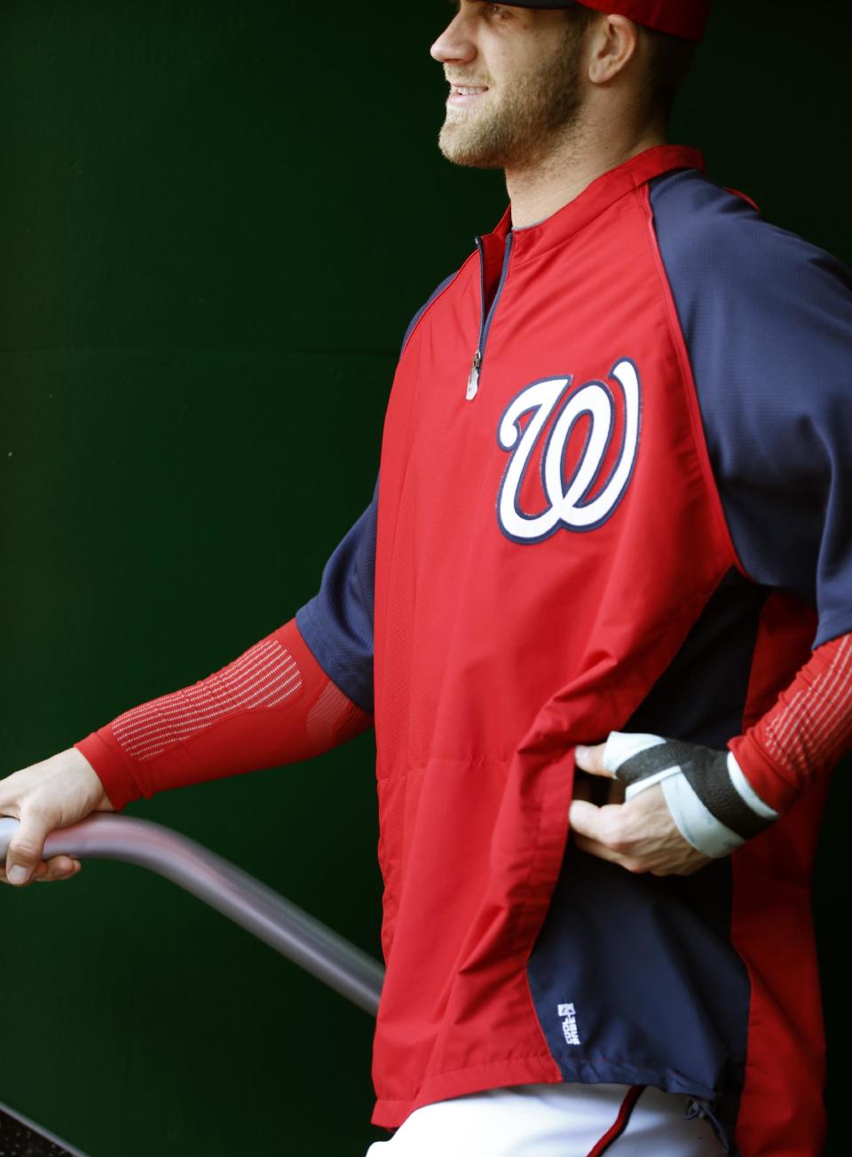 CORRECTS TO LEFT HAND, NOT RIGHT - Washington Nationals left fielder Bryce Harper stands in the dugout with a bandage on his left hand during the fifth inning of a baseball game against the San Diego Padres at Nationals Park Saturday, April 26, 2014, in Washington. Harper injured the hand Friday and is not in the lineup Saturday. (AP Photo/Alex Brandon)