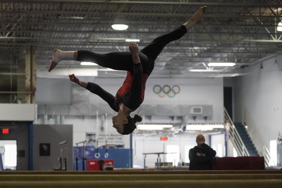 Former world champion and Olympic silver medalist Chellsie Memmel works out with her father and coach Andy Memmel looking on Thursday, Feb. 18, 2021, in New Berlin, Wisc. The 32-year-old rediscovered her love for the sport, so much so the married mother of two is making an unlikely comeback. (AP Photo/Morry Gash)