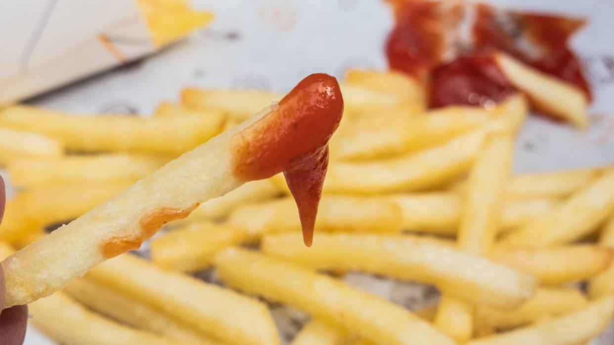 a person eating french fries with ketchup