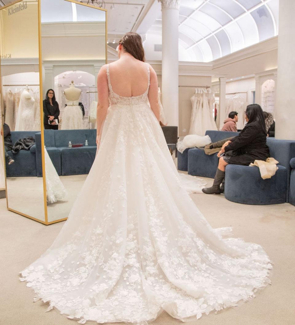 A woman looks at herself in a mirror while she wears a wedding dress.