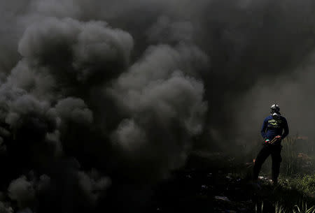 A Palestinian protester looks on as smoke rises from burning tires during clashes with Israeli troops near the Jewish settlement of Beit El, near Ramallah, in the occupied West Bank April 6, 2018. REUTERS/Mohamad Torokman
