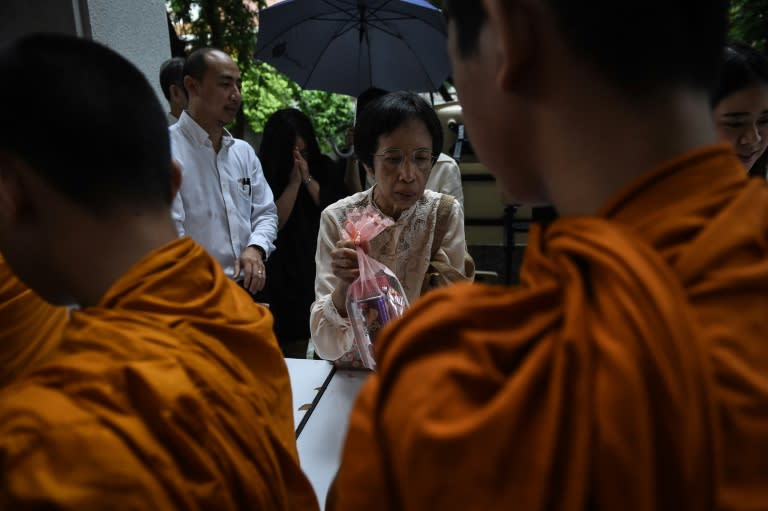 A woman gives alms to monks at a ceremony to commemorate the 40th anniversary of the Thammasat University student massacre in Bangkok on October 6, 2016