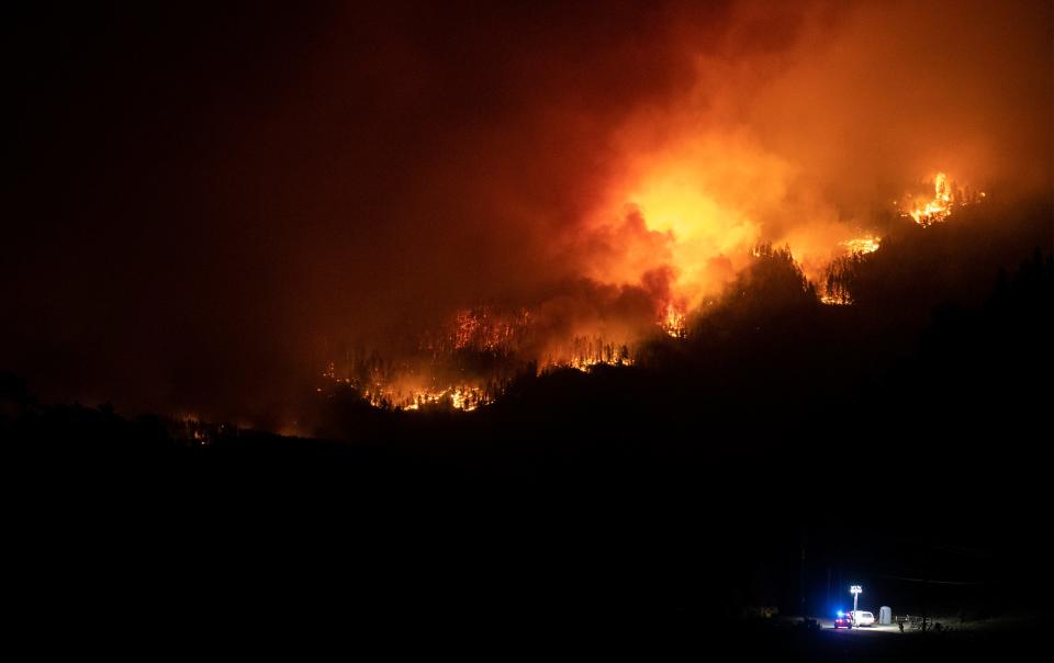 Flames work their way along a ridge near a road block as the Cameron Peak Fire burns outside Estes Park, Colo. on Friday, Oct. 16, 2020.