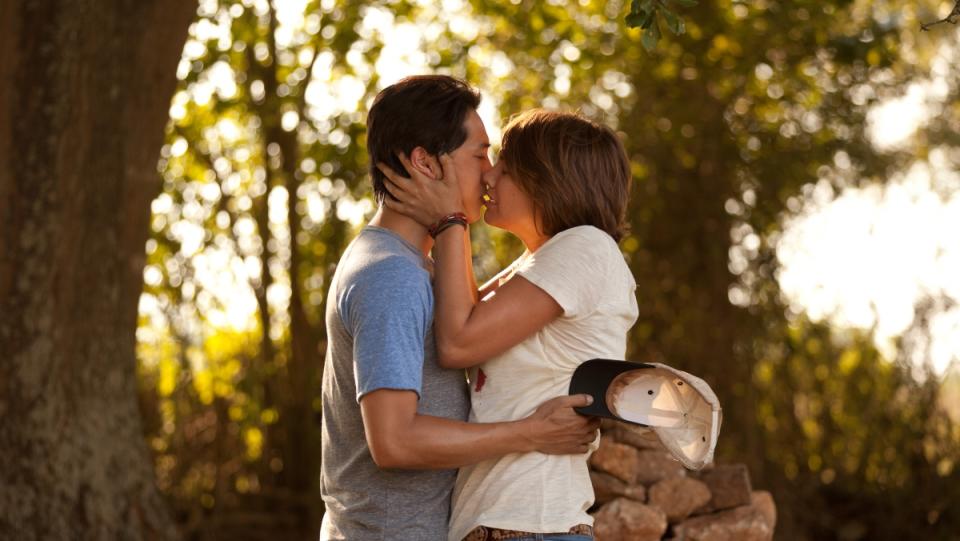 a photo of The Walking Dead characters Glenn and Maggie standing under a tree and kissing in Season 2