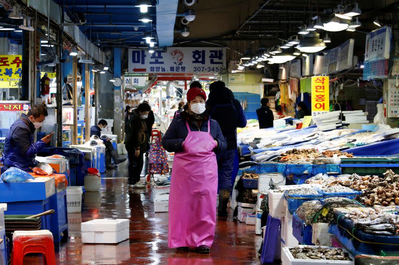 A shopkeeper wearing a mask to prevent contracting the coronavirus waits for a customer at a traditional market in Seoul