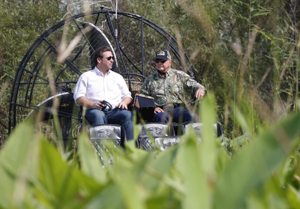 Republican candidate for Florida Governor Ron DeSantis, left, chats with Gladesman and former Florida Fish and Wildlife Conservation commissioner Ron Bergeron during an airboat tour of the Florida Everglades, Wednesday, Sept. 12, 2018, in Fort Lauderdale, Fla. (AP Photo/Wilfredo Lee)