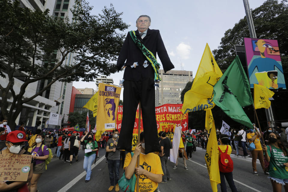 Demonstrators march on Paulista Avenue, one carrying a giant cutout of Brazilian President Jair Bolsonaro, demanding Bolsonaro resign, in Sao Paulo, Brazil, Saturday, July 3, 2021. Activists called for nationwide demonstrations against Bolsonaro, gathering protestors to demand his impeachment amid allegations of potential corruption in the Health Ministry’s purchase of COVID-19 vaccines. (AP Photo/Nelson Antoine)