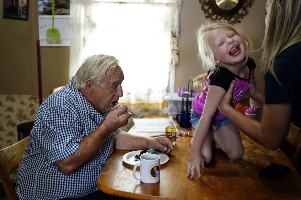 Larry Guess, left, eats a piece of his 72nd birthday cake as his granddaughter Kayla Guess, 31, picks up her daughter Avery Moore, 4, on Thursday, June 23, 2022, in Athens, Ala. His son, David Guess's killing drew little attention outside the rural stretch of northern Alabama where Guess grew up and later worked as a mechanic and truck driver. But his death shattered many lives. (AP Photo/Brynn Anderson)