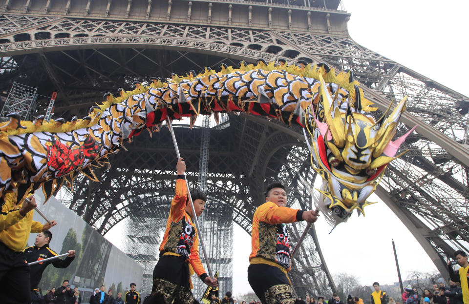 Members of the Chinese community dance with costumes to mark the Chinese New Year at the Eiffel Tower in Paris, Saturday Jan. 25, 2020. This year marks the "Year of the Rat" in the Chinese Lunar calendar. (AP Photo/Michel Euler)