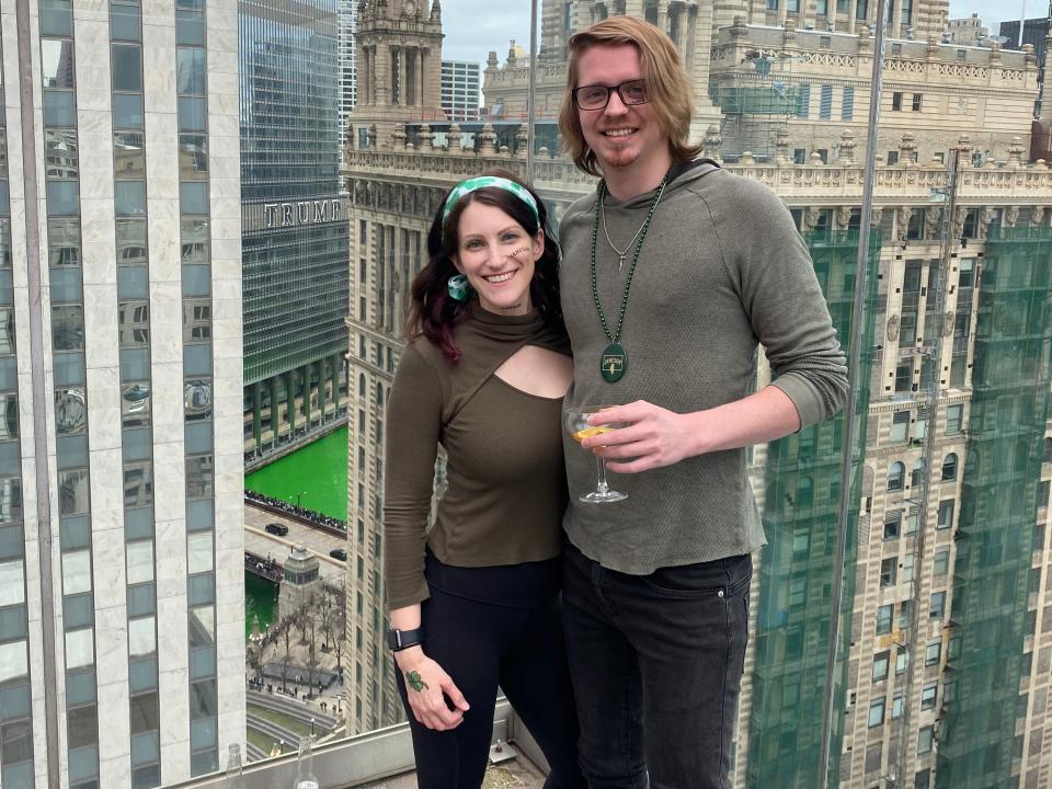 Couple Jennifer Klesman and Derek Moore stand near the window of a sky-rise building.