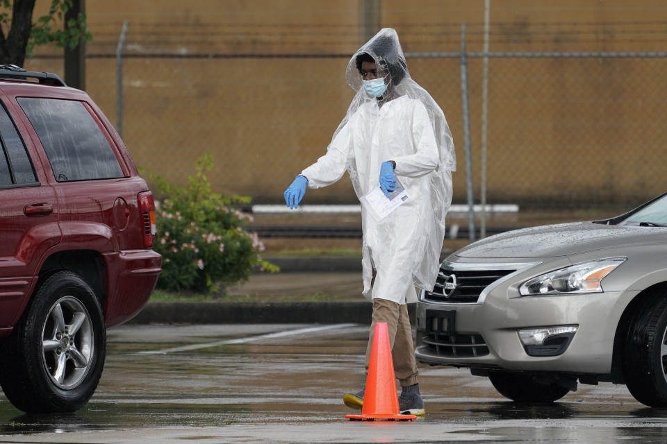 A healthcare worker walks past cars with people waiting to be tested at a United Memorial Medical Center COVID-19 testing site, Wednesday, June 24, 2020, in Houston. Texas Gov. Greg Abbott said Wednesday that the state is facing a "massive outbreak" in the coronavirus pandemic and that some new local restrictions may be needed to protect hospital space for new patients. (AP Photo/David J. Phillip)