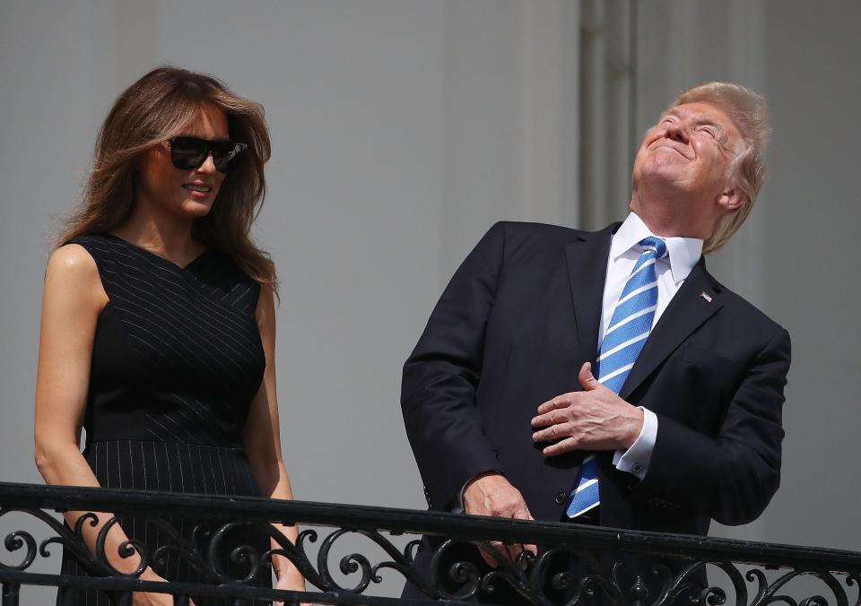 Then-U.S. President Donald Trump looks up toward the solar eclipse without wearing protective glasses, while joined by his wife first lady Melania Trump on the Truman Balcony at the White House on Aug. 21, 2017 in Washington, DC.