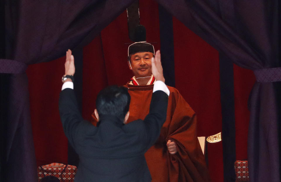 Japan's Prime Minister Shinzo Abe raises his hands as he shouts "banzai" or cheers in front of Emperor Naruhito during a ceremony to proclaim Emperor Naruhito's enthronement to the world, called Sokuirei-Seiden-no-gi, at the Imperial Palace in Tokyo, Japan, Tuesday, Oct. 22, 2019. (Issei Kato/Pool Photo via AP)