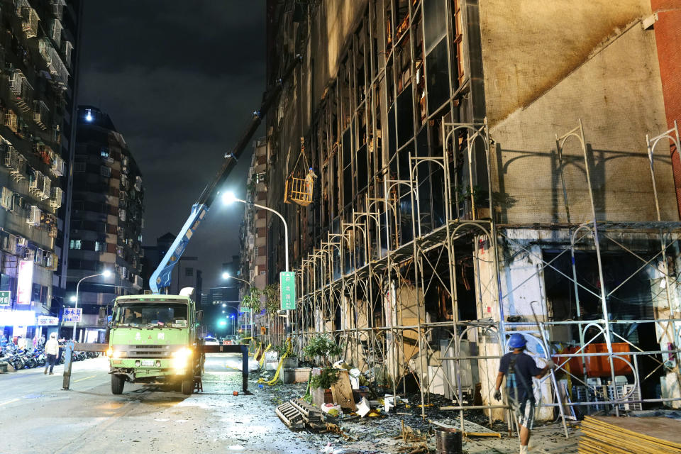 Workers break the glass windows of a building after a fire to prevent further hazard in Kaohsiung in southern Taiwan, Thursday, Oct. 14, 2021. Officials say at least 46 people were killed and over 40 injured after a fire broke out in a decades-old mixed commercial and residential building in the Taiwanese port city of Kaohsiunging. Neighborhood residents say the 13-story building was home to many poor, elderly and disabled people and it wasn’t clear how many of the 120 units were occupied. (AP Photo/Huizhong Wu)