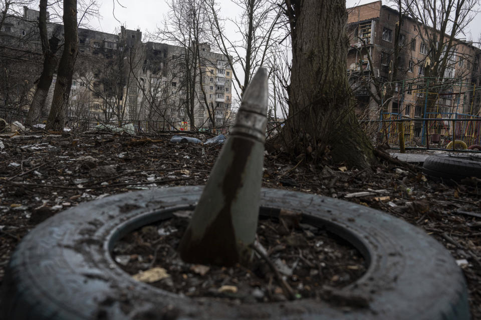 A part of a rocket sticks from a ground in front of a residential building which was heavily bombed by Russian forces in the frontline city of Vuhledar, Ukraine, Saturday, Feb. 25, 2023. (AP Photo/Evgeniy Maloletka)
