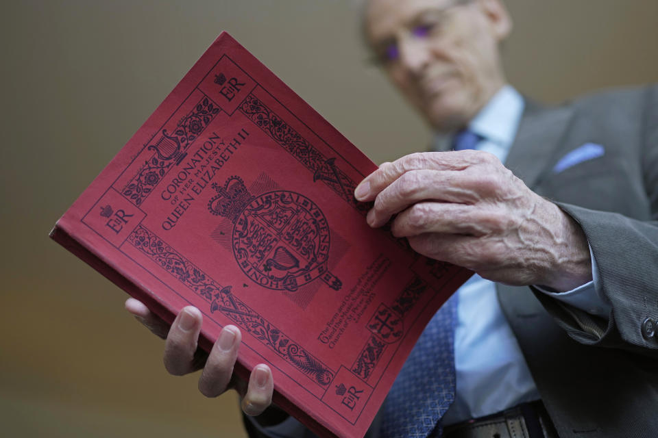 James Wilkinson holds a book of hymns used during Queen Elizabeth II's coronation on June 2, 1953 at Westminster Abbey as Wilkinson recalled his experiences as a child singing in the Westminster Abbey choir during an interview in London, April 17, 2023. The choristers spent months preparing for the service, learning the music and lyrics to the hymns they would sing during the three-hour long ceremony. Wilkinson knew he was part of something extraordinary, so the future BBC journalist recorded everything he saw, in a looping script on the now-yellowed pages of his diary. (AP Photo/Kin Cheung)