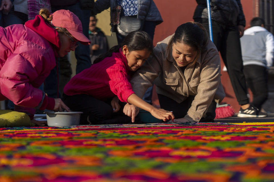 Members of the Alvarez family add the finishing touches to their sawdust carpet in preparation for a Holy Week procession in Antigua, Guatemala, on Good Friday, March 29, 2024. (AP Photo/Moises Castillo)