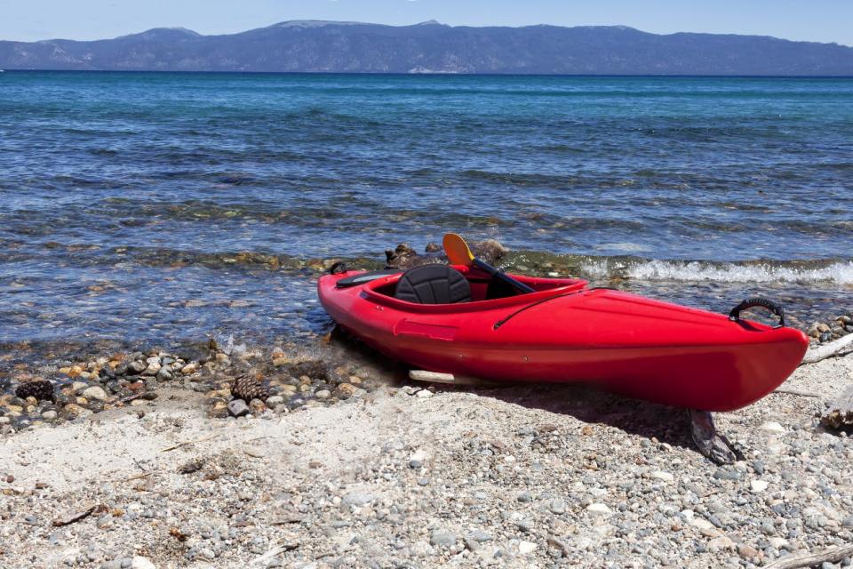 A bright red kayak rests on the shore of Lake Tahoe