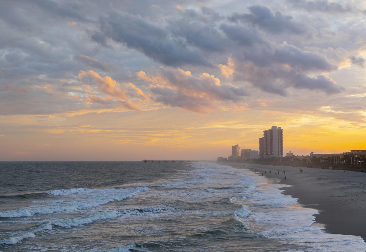 Sunset at Myrtle Beach, South Carolina during fall, closeup of ocean waves hitting the sandy beach with hotels in the background