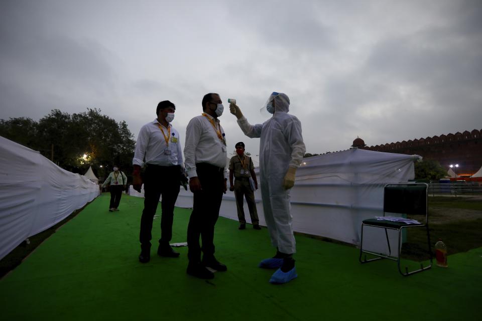 A man dressed in protective suit checks the body temperature of attendees before the start of the Independence Day ceremony on the ramparts of the landmark Red fort monument in New Delhi, India, Saturday, Aug. 15, 2020. India’s coronavirus death toll overtook Britain's to become the fourth-highest in the world with another single-day record increase in cases Friday. (AP Photo/Manish Swarup)