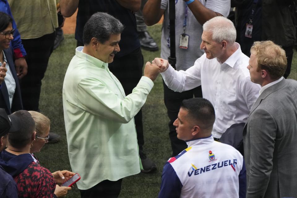 Venezuela's President Nicolás Maduro, left, bumps fists with Russian Sports Minister Oleg Matytsin, at the Alba Games' opening ceremony inside the baseball stadium in La Guaira, Venezuela, Friday, April 21, 2023. (AP Photo/Ariana Cubillos)