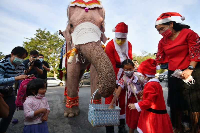 Students receive face masks from an elephant dressed as Santa Claus, in an effort to help prevent the spread of the coronavirus disease (COVID-19), ahead of Christmas celebrations at a school in Ayutthaya