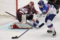 Latvia's goalkeeper Kristers Gudlevskis, left, makes a save in front of Slovakia's Peter Cehlarik during the preliminary round match between Slovakia and Latvia at the Ice Hockey World Championships in Ostrava, Czech Republic, Sunday, May 19, 2024. (AP Photo/Darko Vojinovic)