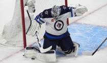 Winnipeg Jets goaltender Connor Hellebuyck makes a pad-save in the first period of Game 4 of an NHL Stanley Cup first-round playoff series against the Colorado Avalanche, Sunday, April 28, 2024, in Denver. (AP Photo/David Zalubowski)