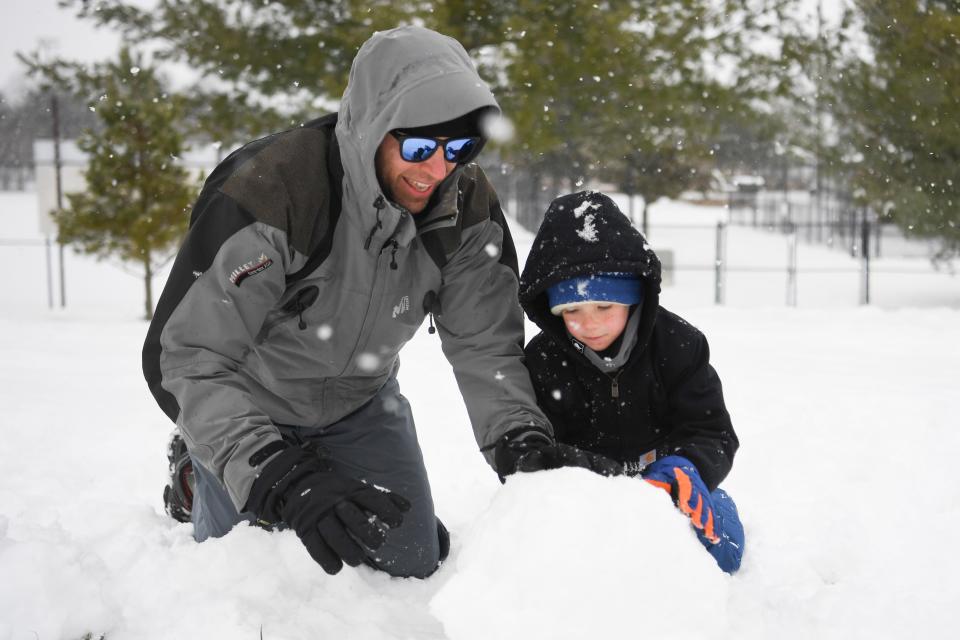 At left, Seth Nutter helps Dylan Mezick, 8, build a snowman, Friday, Jan. 19, 2024.