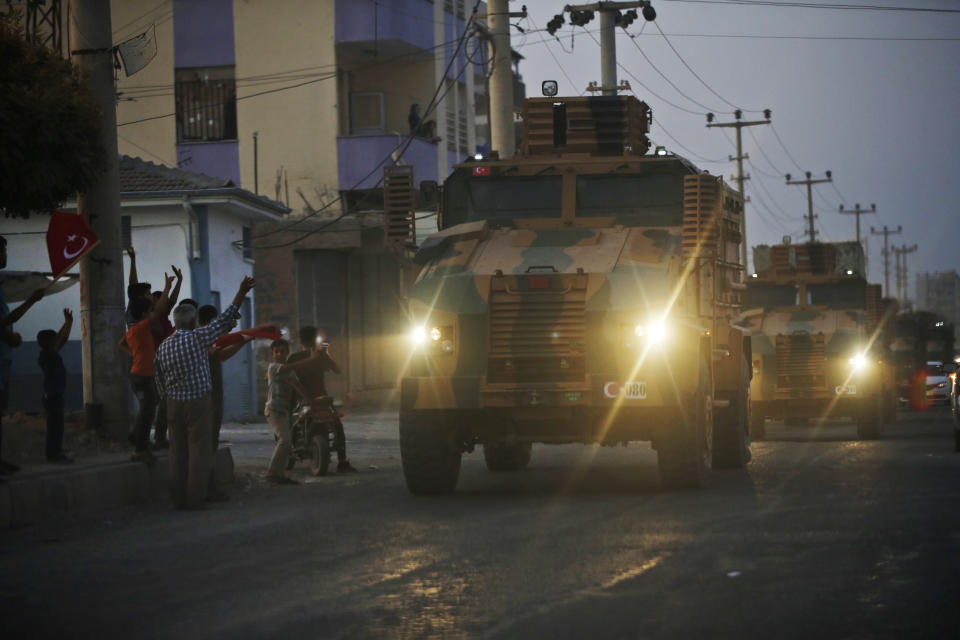 FILE-In this Wednesday, Oct. 9, 2019 file photo, shortly after the Turkish operation inside Syria had started, local residents cheer and applaud as a convoy of Turkish forces vehicles is driven through the town of Akcakale, Sanliurfa province, southeastern Turkey, at the border between Turkey and Syria. Since Turkey announced its incursion into neighbouring Syria to clear out Kurdish fighters last week, patriotic sentiment has run high with many public signs of support for the military. (AP Photo/Lefteris Pitarakis, File)