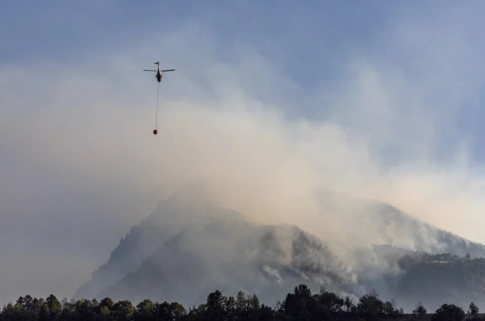 A helicopter carries water to a wildfire on the flank of a mountain in Bitsch near Brig, Switzerland, July 18, 2023. REUTERS/Denis Balibouse