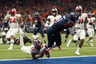 UTSA running back Sincere McCormick (3) leaps through the hands of Western Kentucky defensive back Miguel Edwards (13) for a touchdown during the second half of an NCAA college football game for the Conference USA championship Friday, Dec. 3, 2021, in San Antonio. (AP Photo/Eric Gay)