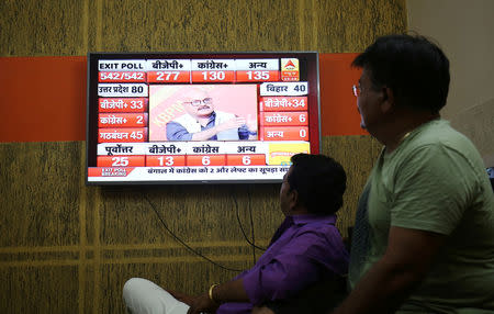 Men look at a television screen showing exit poll results after the last phase of the general election in Ahmedabad, May 19, 2019. REUTERS/Amit Dave