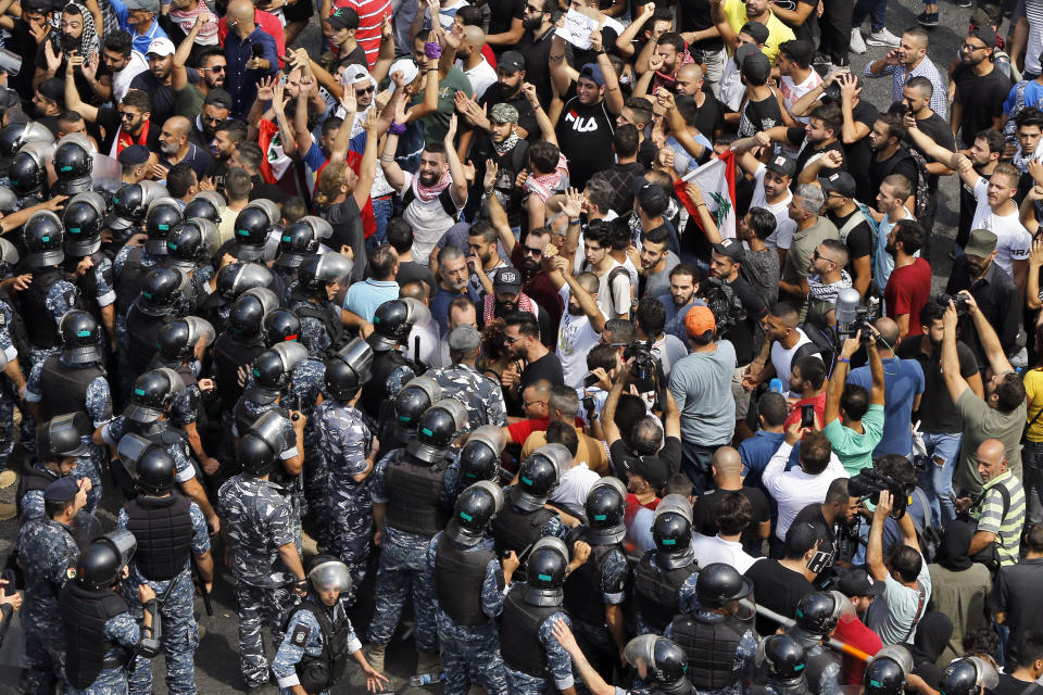 Anti-government protesters chant slogans as riot policemen close the road to the government house during a demonstration, in downtown Beirut, Lebanon, Sunday, Sept. 29, 2019. Hundreds of Lebanese are protesting an economic crisis that has worsened over the past two weeks, with a drop in the local currency for the first time in more than two decades. (AP Photo/Bilal Hussein)