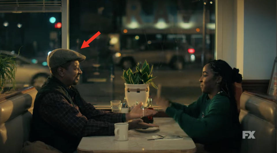 Robert Townsend and Ayo Edebiri sitting at a diner table holding hands