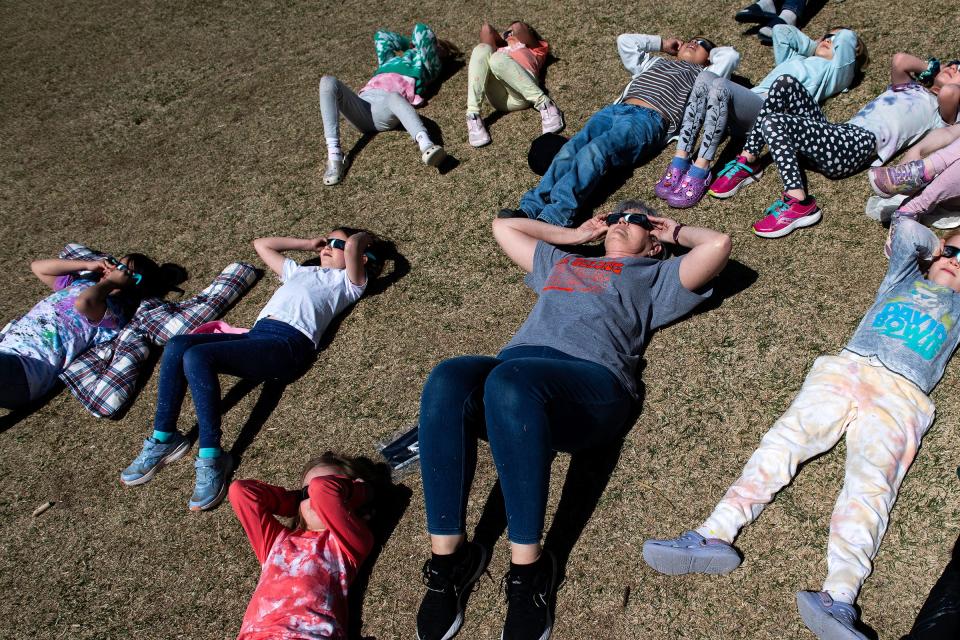 Science and engineering teacher Lisa Musante sits with a class of students during the partial solar eclipse at Tavelli Elementary School in Fort Collins on Monday.