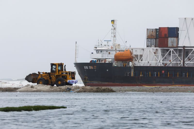 A wheel loader clears the ground near stranded cargo ship MV Heng Tong 77 at Sea View beach in Karachi