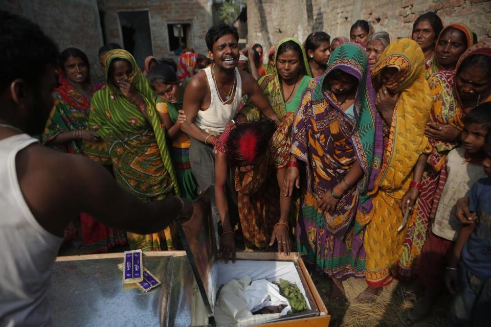 In this Wednesday, Nov. 23, 2016 photo, Saro Kumari Mandal, 26, cries as she leans on the coffin carrying her husband Balkisun Mandal Khatwe, 26, a migrant worker who died in his sleep in Qatar, at Belhi village, in Saptari district, Nepal. The number of Nepali workers going abroad has more than doubled since the country began promoting foreign labor in recent years: from about 220,000 in 2008 to about 500,000 in 2015. Yet the number of deaths among those workers has risen much faster in the same period. But now medical researchers say these deaths fit a familiar pattern: Every decade or so, dozens, or even hundreds, of seemingly healthy Asian men working abroad in poor conditions start dying in their sleep. The suspected killer even has a name: Sudden Unexplained Nocturnal Death Syndrome. (AP Photo/Niranjan Shrestha)
