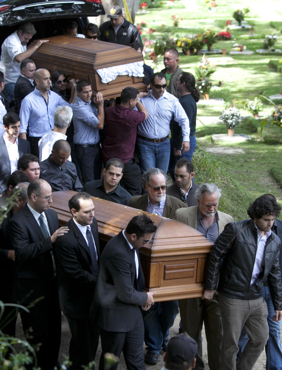 Relatives and friends carry the remains of Monica Spear, below, and of her ex-husband Thomas Henry Berry, top, during their funeral at the East Cemetery in Caracas, Venezuela, Friday, Jan. 10, 2014. Robbers killed actress Spear, 29, and her former husband Berry, 39, late Monday night on an isolated stretch of highway while the couple was returning to the capital by car with their 5-year-old daughter from a vacation. (AP Photo/Alejandro Cegarra)