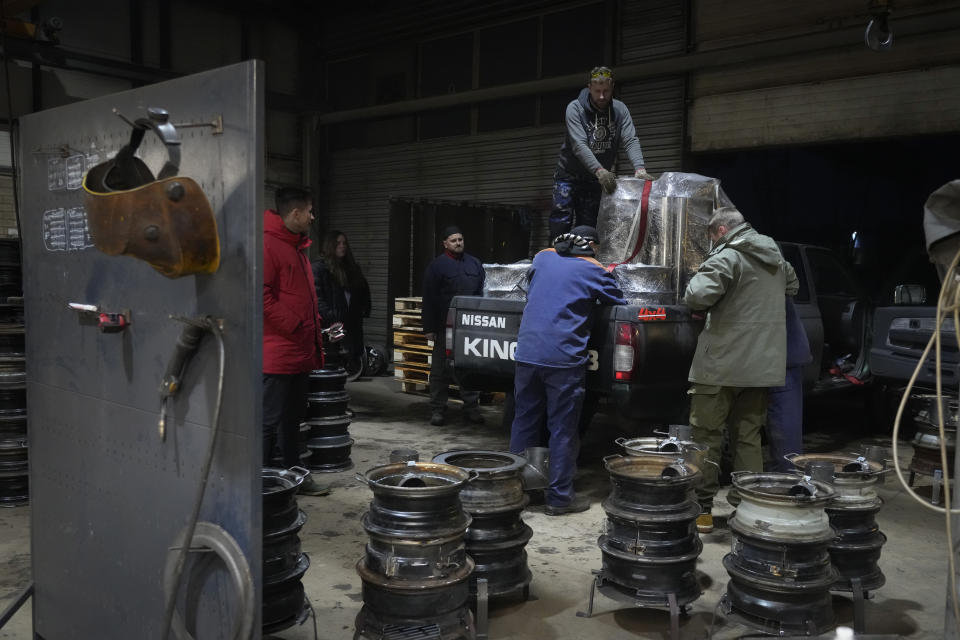 Volunteers load heating stoves into a truck to deliver them to Ukrainians, in a workshop in Siauliai, some 230 km (144 miles) north-west of the capital Vilnius, Lithuania, Thursday, Feb. 2, 2023. In a dusty workshop in northern Lithuania, a dozen men transform hundreds of wheel rims into potbelly stoves to warm Ukrainians huddled in trenches and bomb shelters. (AP Photo/Sergei Grits)