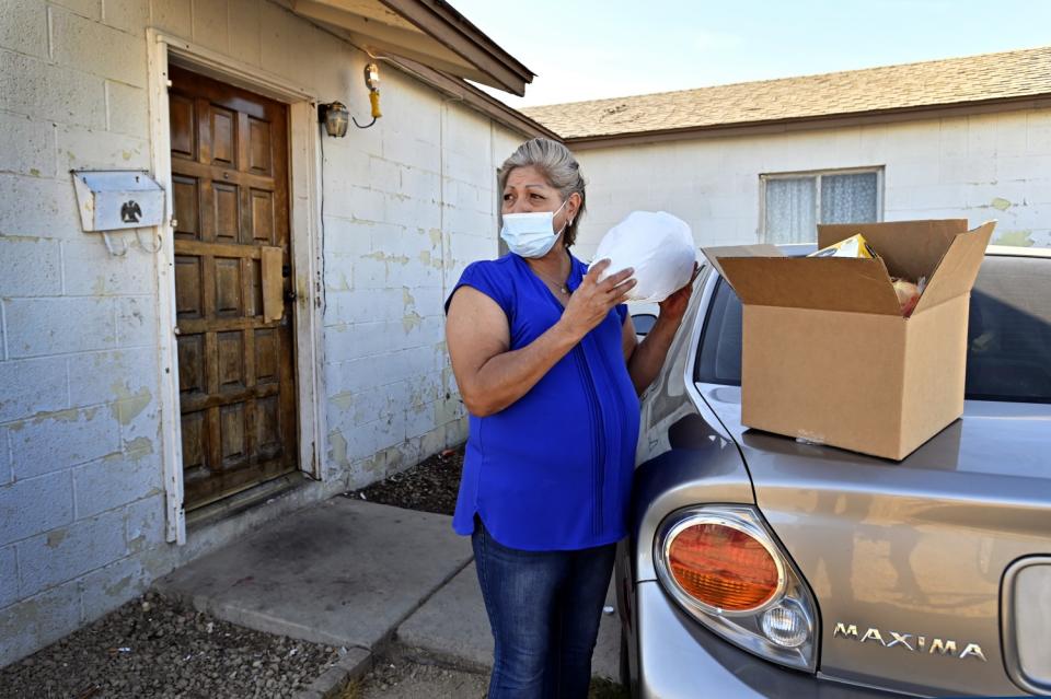 Norma Flores shows off her Thanksgiving dinner after receiving it from the Fall Giving Pop-Up.