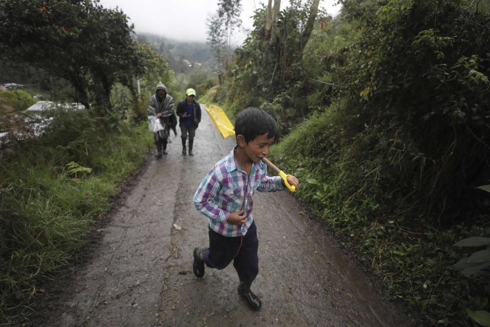 Jeimmer Alejandro Riveros, 9, carries a shovel, followed by his mother, Nubia Rocio Gaona, 37, and his brother David, 14, as they walk on a road that leads to their small farm in Chipaque, Colombia, Saturday, May 9, 2020. The small-time farming mother and two sons are reinventing themselves as YouTubers due to a quarantine ordered by the government to contain the spread of COVID-19, teaching others how to grow vegetables at home and providing self-starter kits that they deliver through a local courier. (AP Photo/Fernando Vergara)